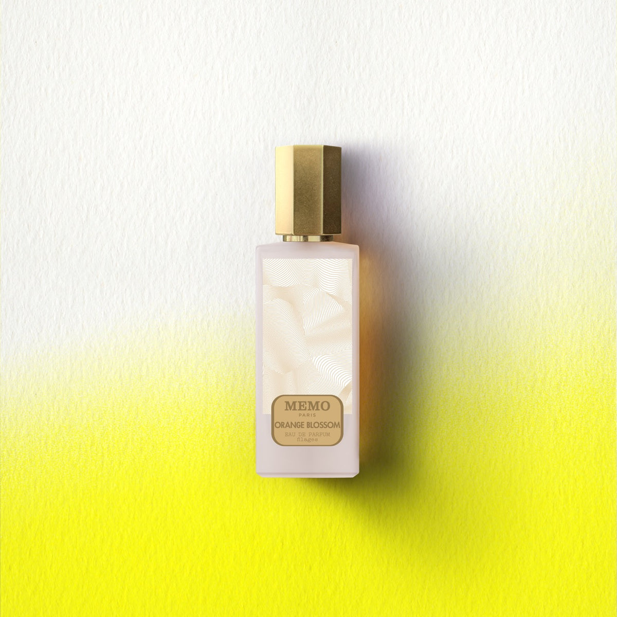 A sleek frosted glass memo paris essences filages orange blossom eau de parfum bottle with a polished gold cap